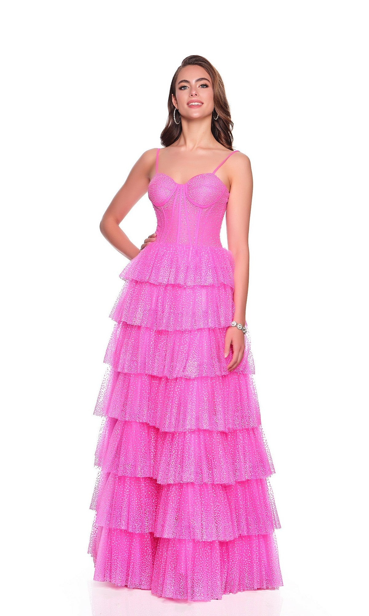 A woman stands against a white background in the Dave and Johnny 12397 long prom dress—a fuchsia pink, floor-length tiered ruffle gown with spaghetti straps and a corset bodice.